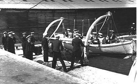 In this 1956 picture, Vice-Admiral Sir Geoffrey Robson KBE CB DSO RN watches as Cadets lower a 27-foot whaler in radial davits during an â€œabandon shipâ€ exercise. Captain G. V. Legassick the Captain-Superintendent also observes â€“ with a view to future critical comment. When the whaler was slipped, the Cadets manning the boat-rope energetically hauled its bow to starboard and out towards the entrance of the boatpen. By the time the boatrope was slipped and the oars shipped, it was moving at an impressive speed toward other boats moored in the harbour.